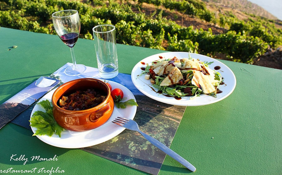 ceramic bowl with meet and tomatoes sauce and plate with green salade at 'Manalis Winery' restaurant